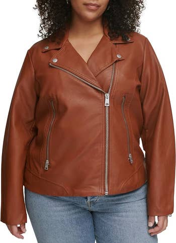 Model wears a brown leather jacket with zipper details for a shopping article