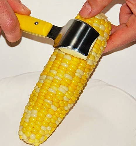hand using tool to butter corn
