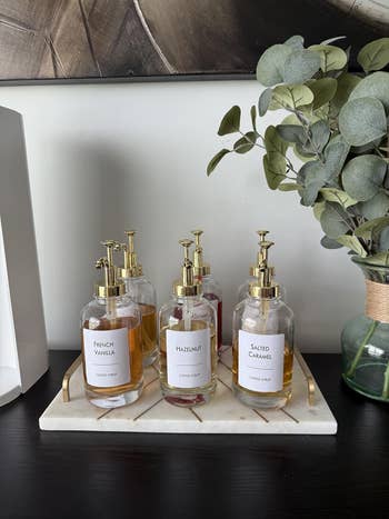 Coffee syrup bottles labeled French Vanilla, Hazelnut, and Salted Caramel connected a tray beside a vase with eucalyptus leaves
