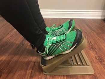reviewer photo of them using the adjustable footrest and wearing green sneakers