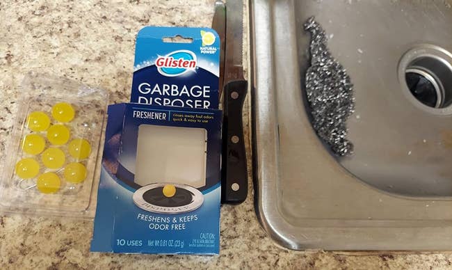 A reviewer's garbage disposer balls alongside their packaging and a garbage disposal