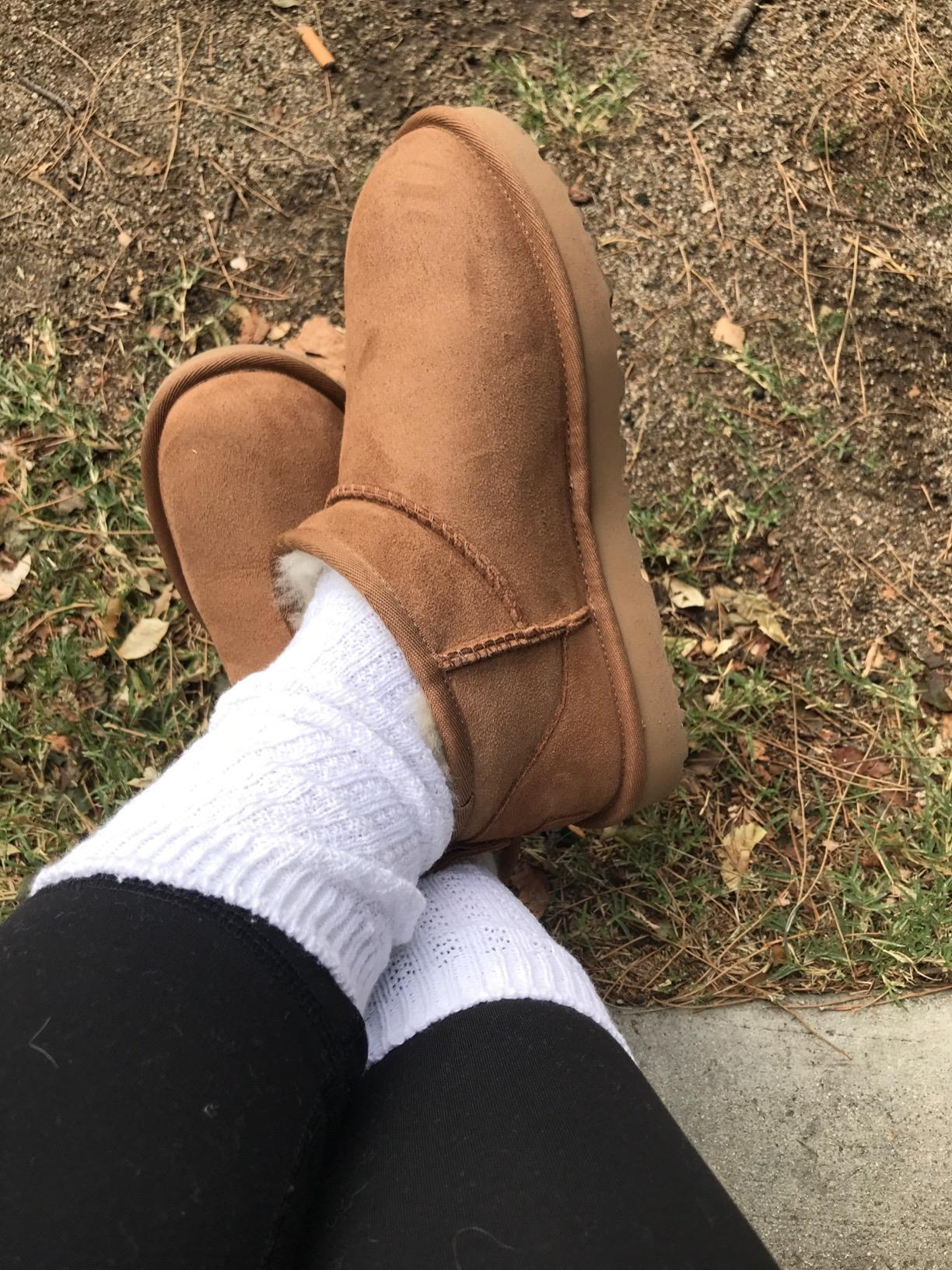 Close-up of a reviewer's feet successful  brownish  uggs, achromatic  socks, and achromatic  leggings connected  writer  and ungraded   background