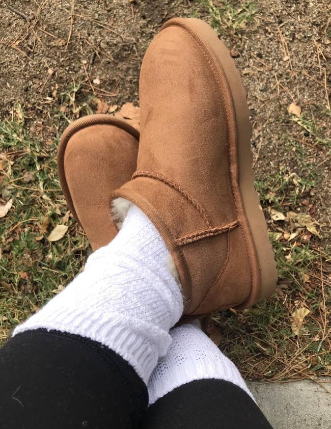 Close-up of a reviewer's feet successful brownish uggs, achromatic socks, and achromatic leggings connected writer and ungraded background