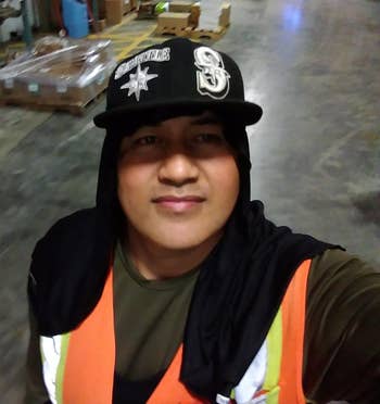 A reviewer wearing the cooling hoodie in black under a cap
