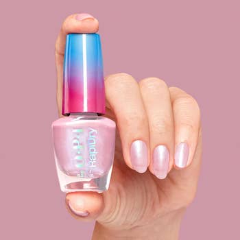 Hand holding a vessel  of pinkish  OPI nail polish 