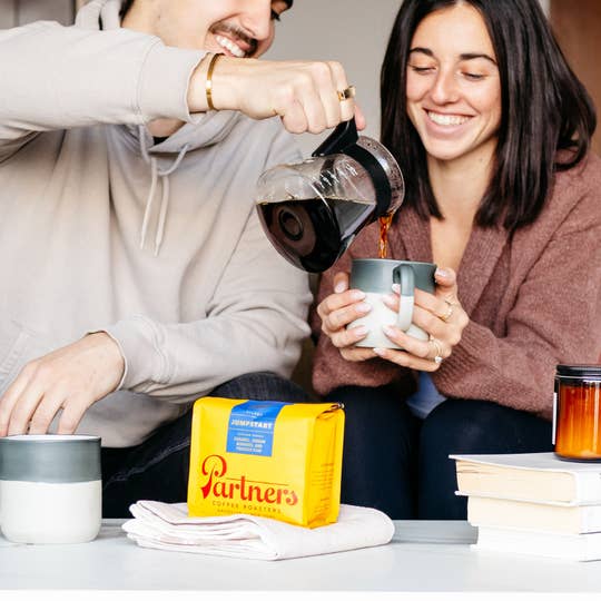 a couple enjoying coffee with a partners coffee bag in front of them