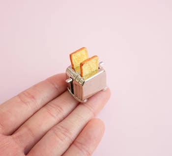 Miniature toaster ring with two tiny pieces of toast. Perfect for quirky jewelry enthusiasts