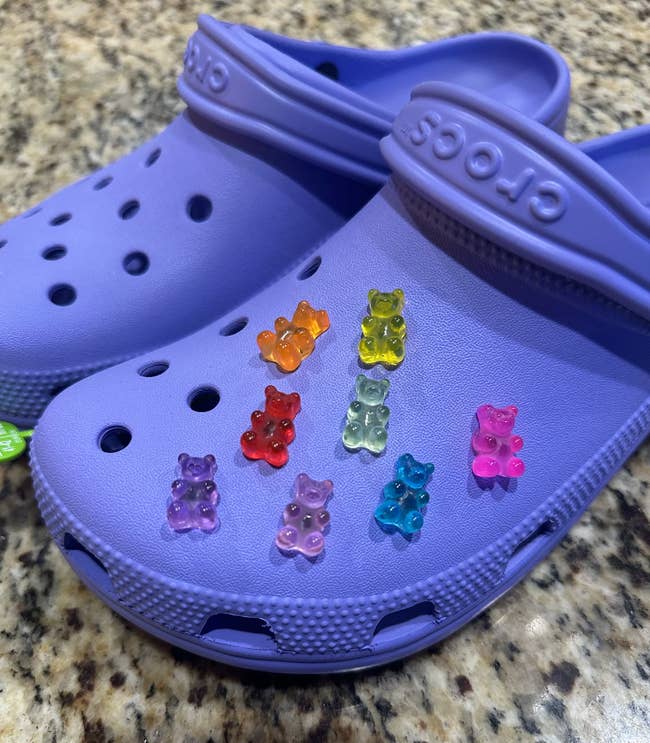 orange, yellow, purple, pink, red, blue, green, and purple gummy bear charms on purple Crocs