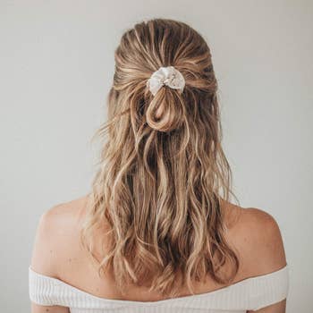 a model with a white shimmery scrunchie in her hair