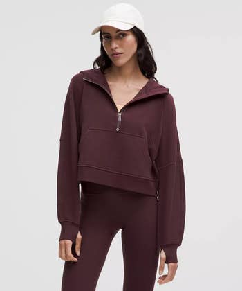 Person wearing a casual hoodie and leggings, accessorized with a cap, showcasing a sporty, comfy  look   suitable for activewear shopping
