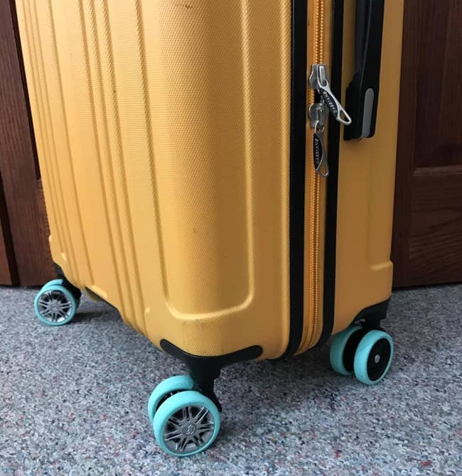 Yellow suitcase with blue wheels, partially open with a padlock