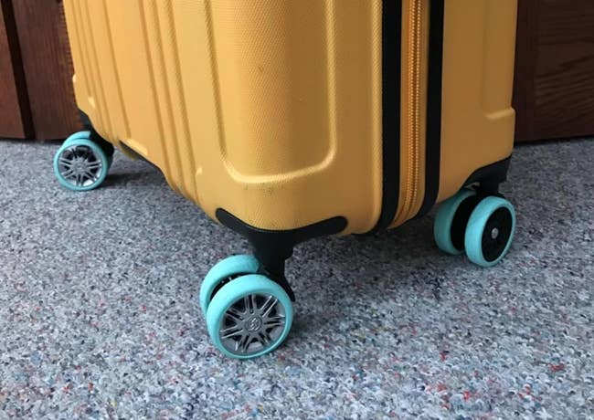 Yellow suitcase with blue wheels, partially open with a padlock
