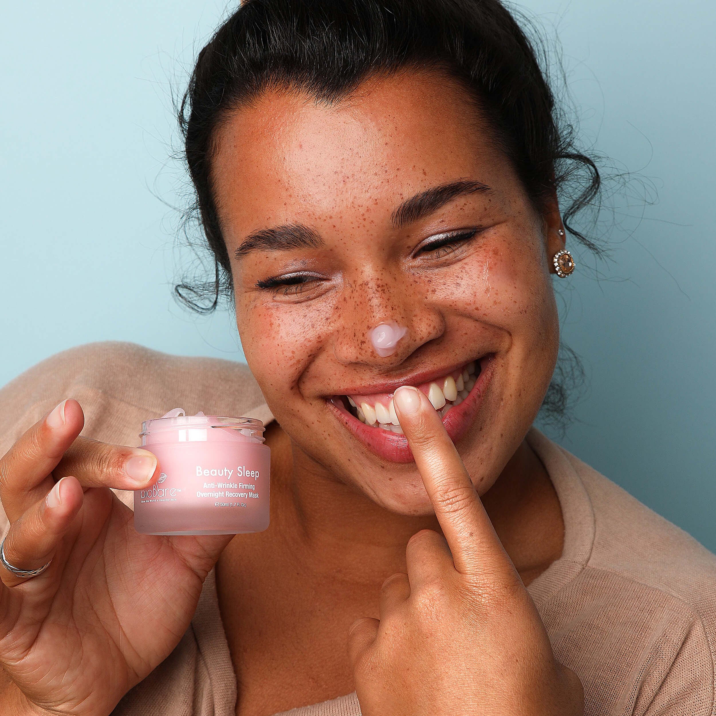 model applies pink Beauty Sleep Recovery Mask to their cheeks