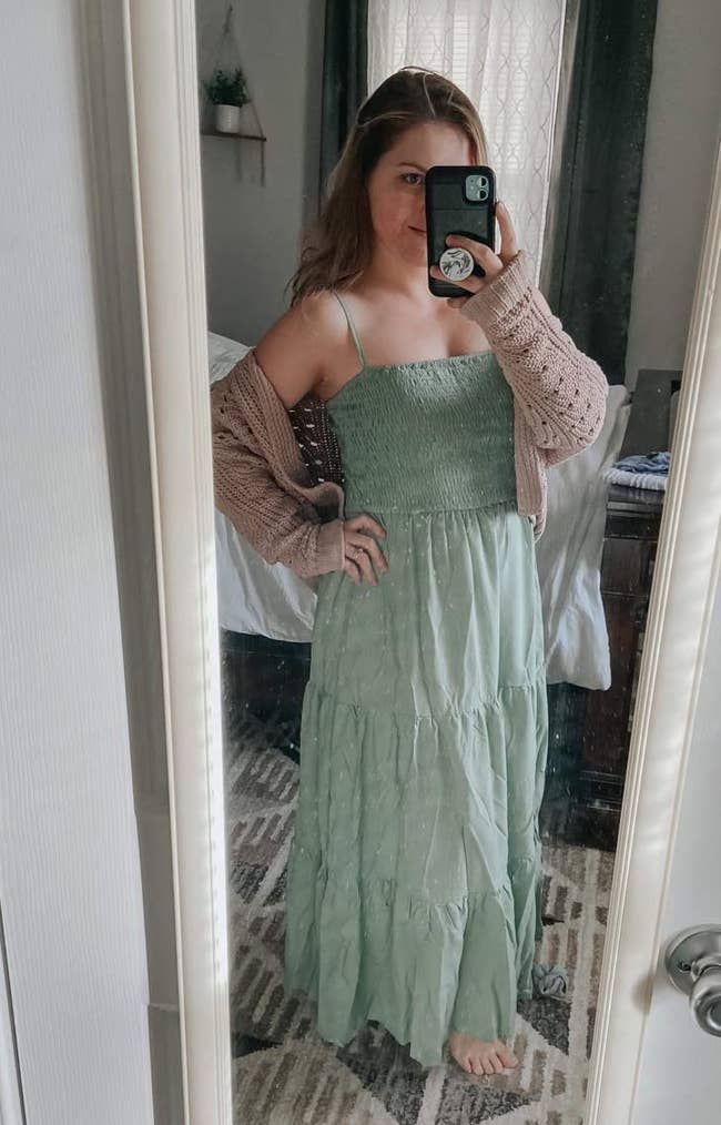 Reviewer wearing tiered sage green dress in front of a mirror