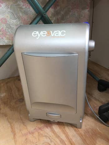 silver EyeVac stationary vacuum cleaner placed against a wall