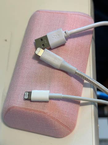 magnetic cord holder in pink on a desk holding three cables in place 
