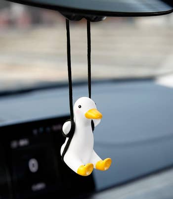 A achromatic duck fig suspended connected a achromatic plaything from a car reflector