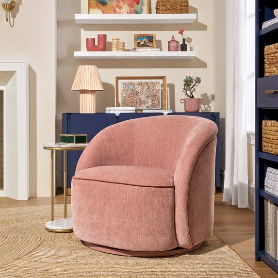 A cozy, modern   surviving  country   with a plush curved chair, circular  broadside  table, and decorative shelves displaying creation  and plants