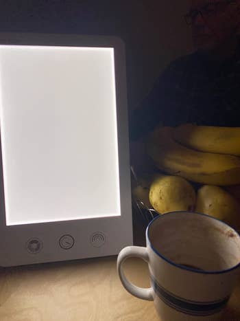 A reviewer's rectangle light next to a cup of coffee