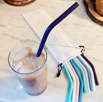 reviewer photo of a glass of iced coffee next to a pack of silicone straws