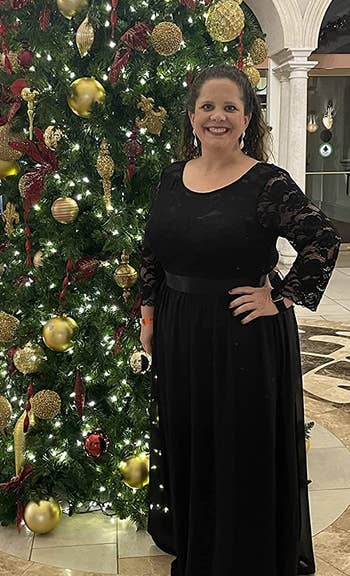 Reviewer wearing long black dress in front of Christmas tree