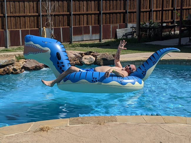 reviewer in large blue t rex float with large head and tail