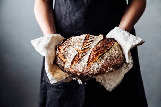 Person holding freshly baked loaf of rustic bread