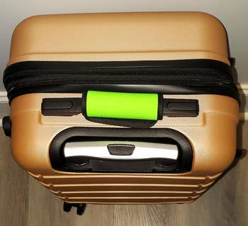 A suitcase with a lime green luggage handle