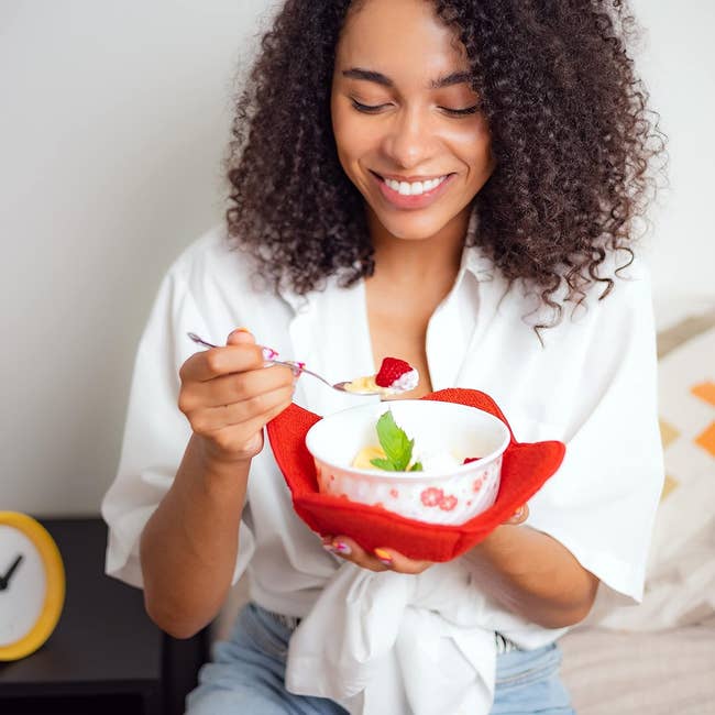 Model holding a bowl of soup resting in a red cloth holder 