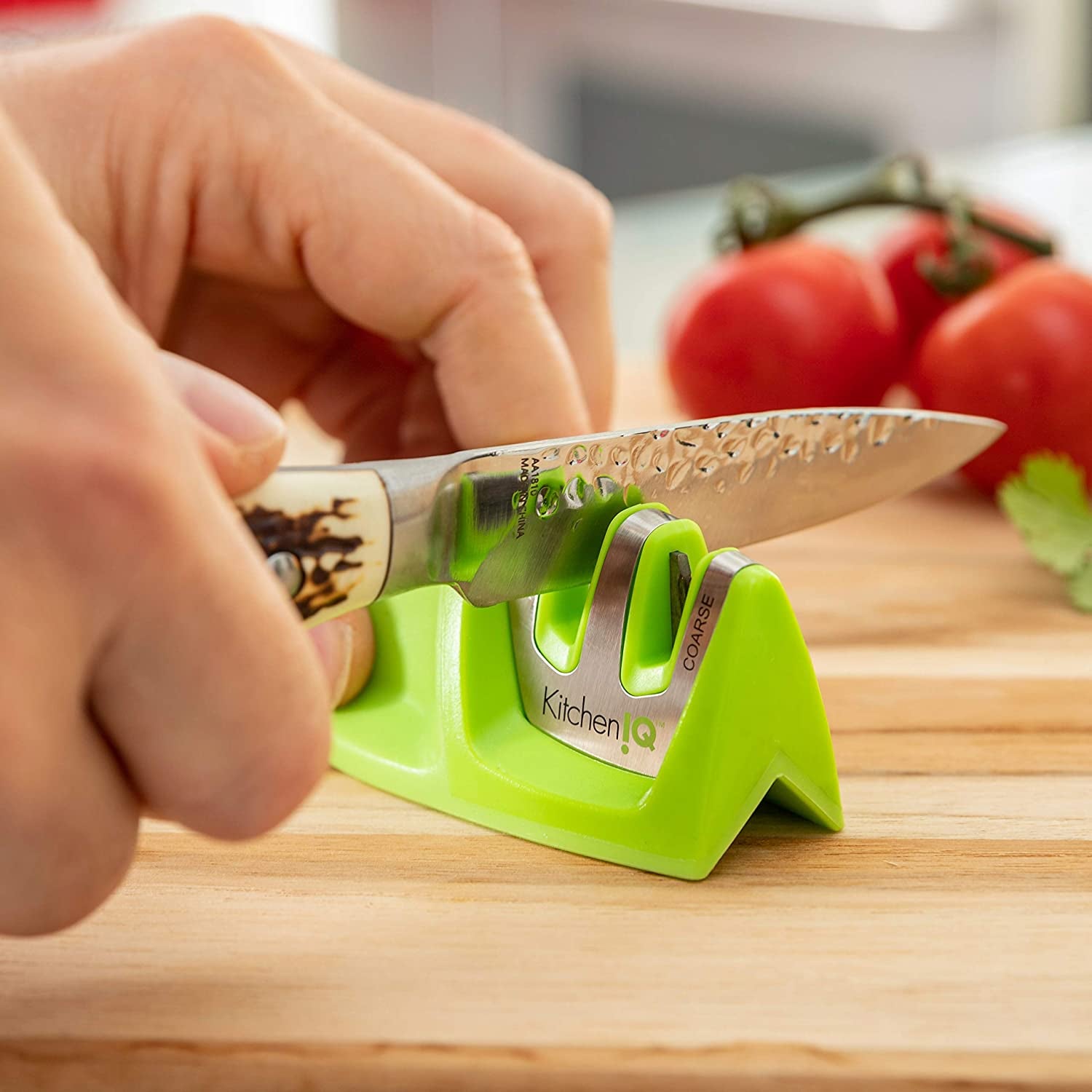 Hands running a knife through the small green sharpener