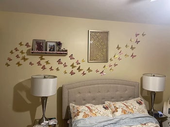 Reviewer's gold and rose gold butterflies adorning the wall above their bed