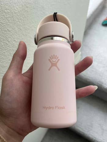 Hand holding a tiny  Hydro Flask vessel  with a handle, perfect  for on-the-go hydration