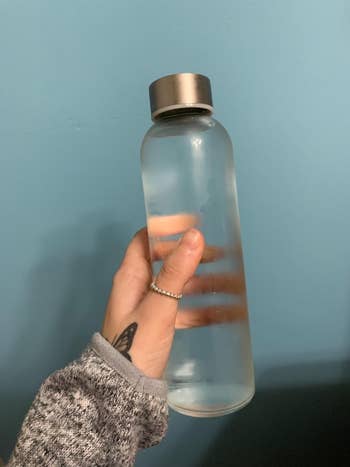 a reviewer holding the clear glass water bottle