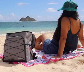 Same reviewer shows front side of the cooler, which has bungee detailing, while relaxing at the beach