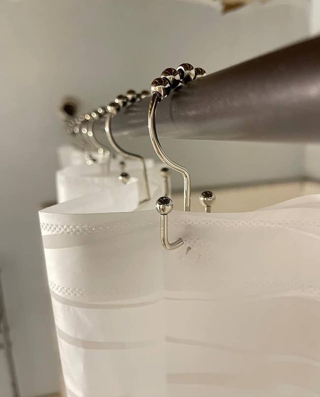 reviewer image of a shoer liner and shower curtain hanging from the double shower curtain rings