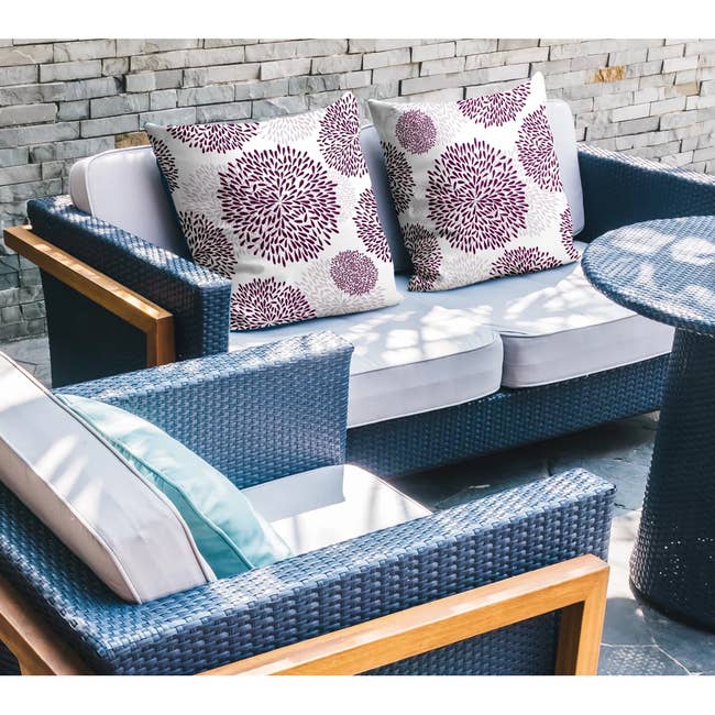 Outdoor patio acceptable   with wicker furniture, featuring a loveseat with decorative floral cushions and a matching azygous  seat  and table