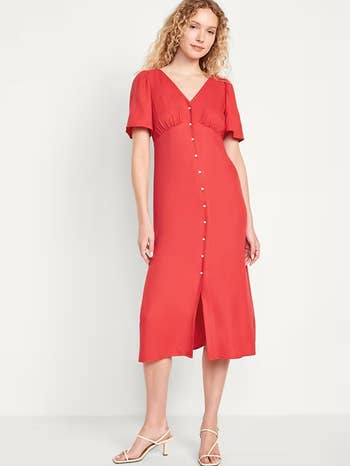 Model in buttoned red midi dress with short sleeves and heeled sandals