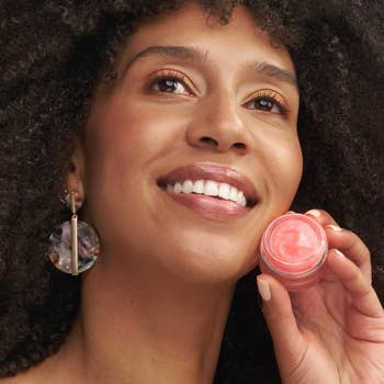 Model holding the lip balm next to their face