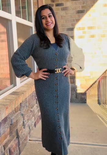 reviewer wearing a ribbed knit buttoned formal with a loop stands smiling. Fashionable outfit suitable for chill weather