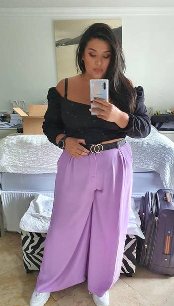 reviewer takes a mirror selfie wearing a puff-sleeve top and wide-leg trousers, accessorized with a belt