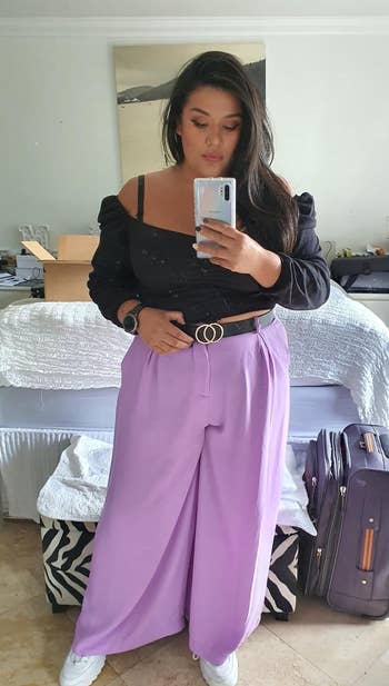 reviewer takes a mirror selfie wearing a puff-sleeve top and wide-leg trousers, accessorized with a belt