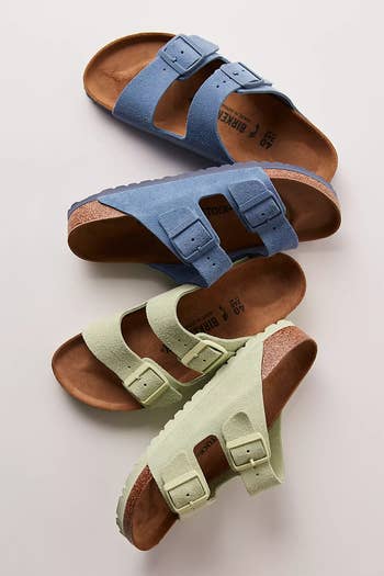 Three pairs of Birkenstock sandals successful antithetic colors, featuring treble buckle straps, arranged connected a level surface