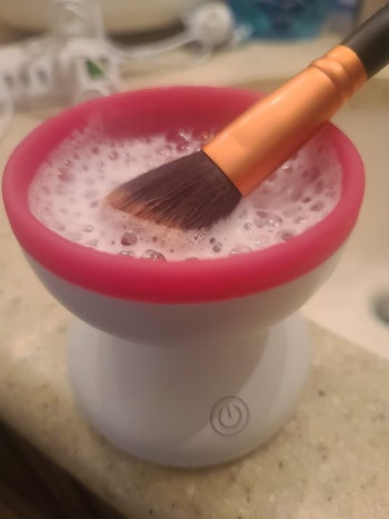 A reviewer cleaning a brush in the machine with foamy water inside