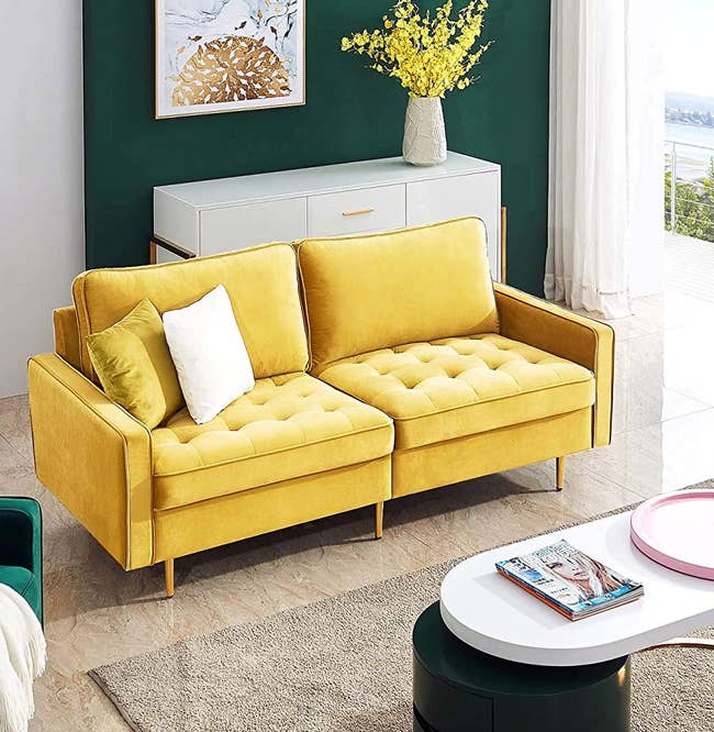 the yellow mid century modern sofa with two pillows on it