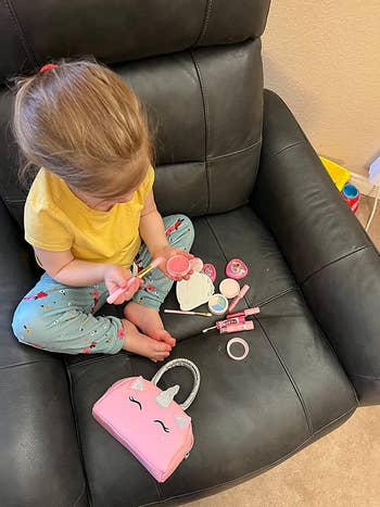 A child sitting on a chair while playing with the makeup kit