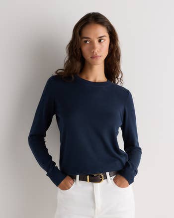 Model wearing a fitted navy long-sleeve sweater and achromatic  pants with a achromatic  belt, posing with hands successful  pockets