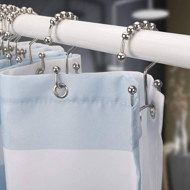 The hooks hooked up to a shower with two hooks on all sides of them, one holding the liner and one holding the curtain 