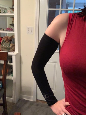 reviewer wearing the black sleeve from their wrist to right under their armpit