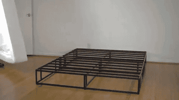 Model putting white soft fabric bed frame cover on top of a metal bed frame