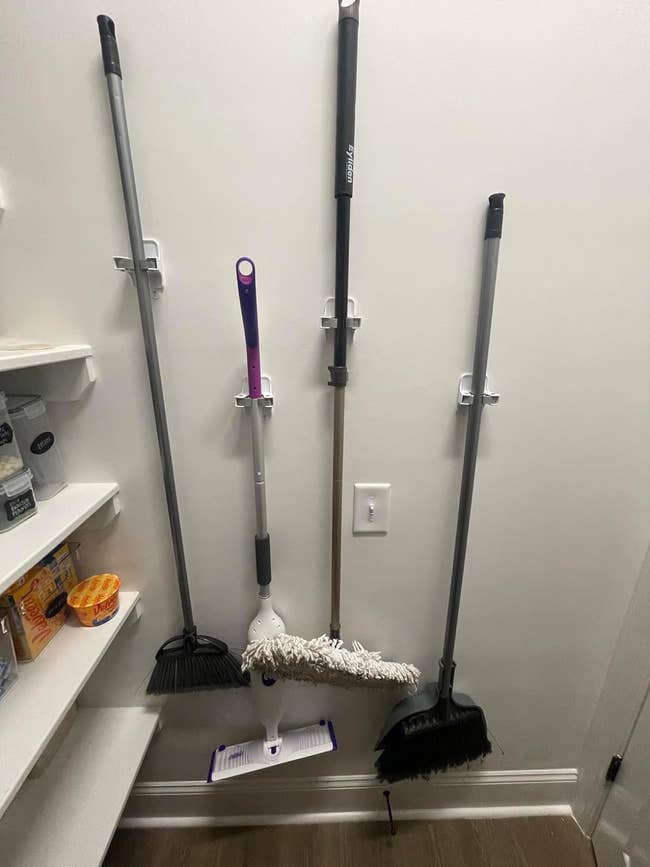 a reviewer's wall with four brooms hanging on it